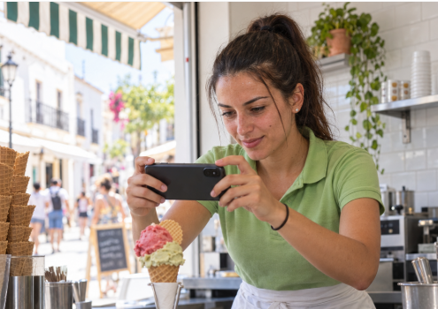 Empleada de una heladería fotografiando un helado con el móvil para crear contenido de redes sociales con IA